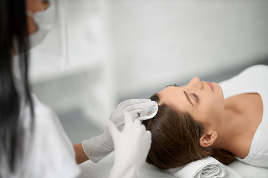 Signs You Need Hair Loss Treatment – A woman receiving a professional scalp evaluation in a modern hair restoration clinic, highlighting early signs of hair thinning and the need for expert hair loss treatment.